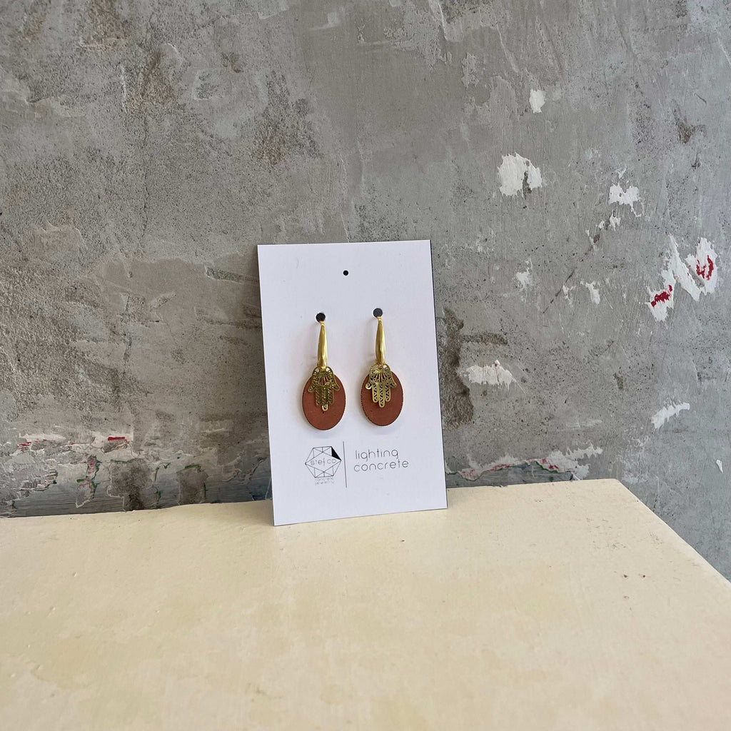 Chamsa hook earrings combined with brown concrete drop-shaped background  by Stef.co