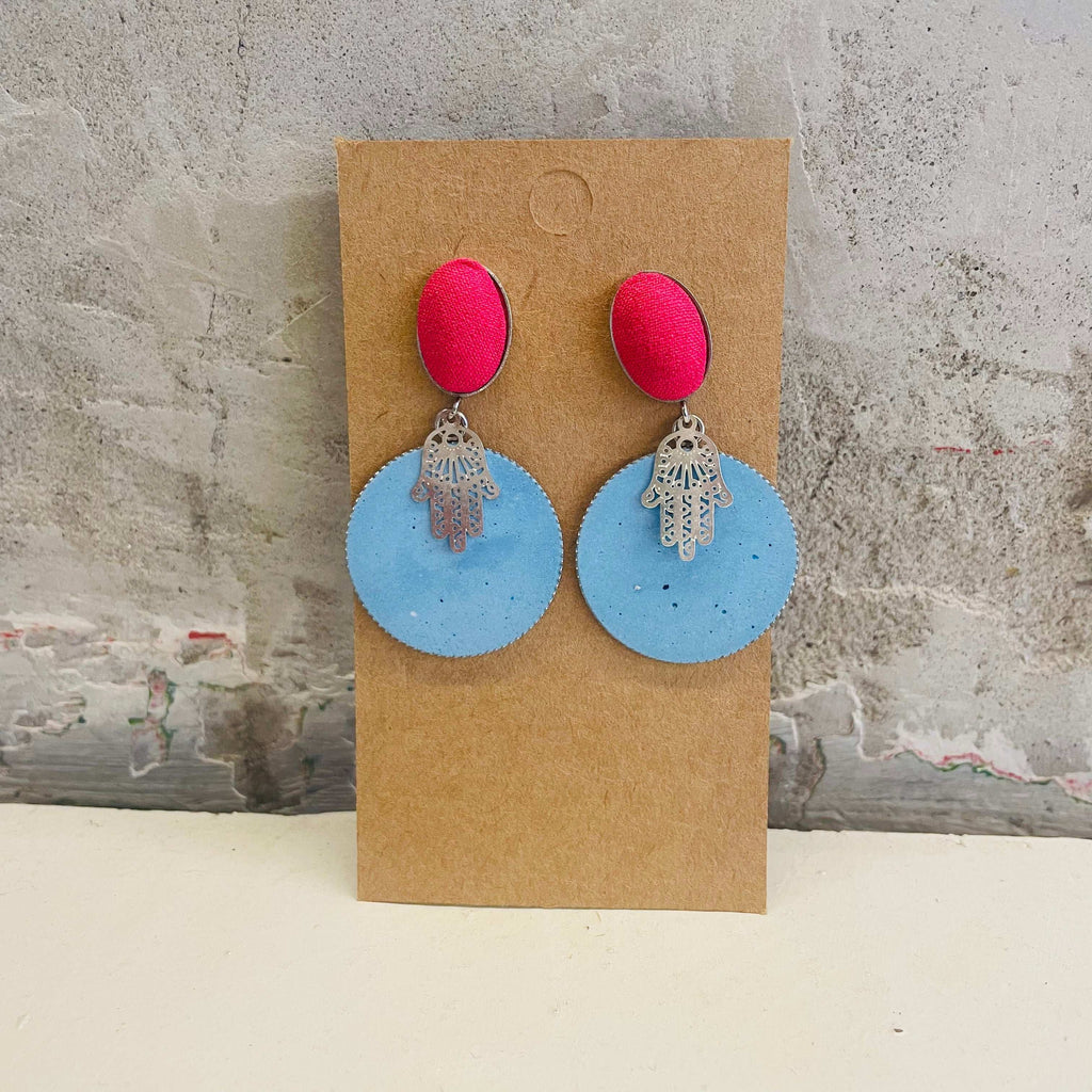 Chamsa earrings with a blue, round concrete piece and a pink extra by Stef.co