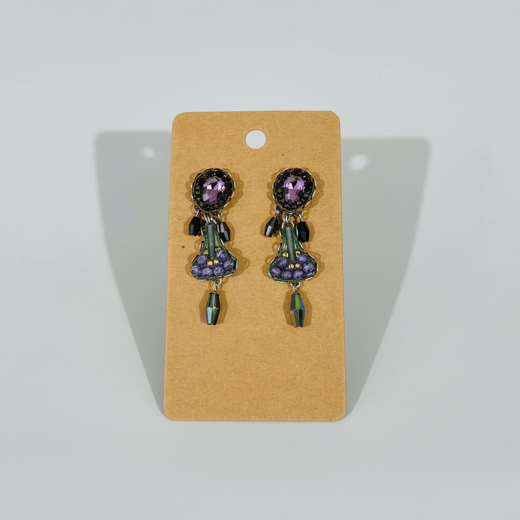Pair of earrings on a brown card against a textured white background